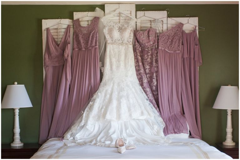 Wedding gown and bridesmaids dresses hanging on wall at The Oaks by Melissa Grimes-Guy Photography