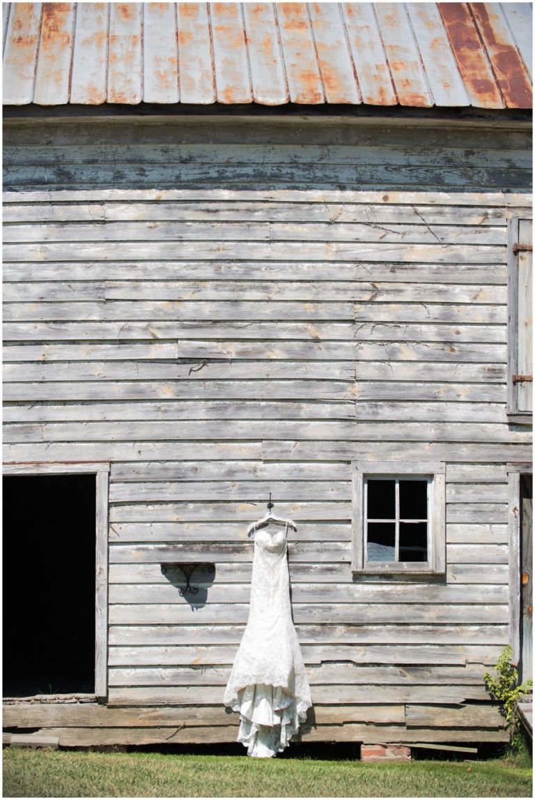 Pretty wedding dress hangs on old barn at The Oaks Waterfront Inn in St. Michaels, MD by Melissa Grimes-Guy Photography